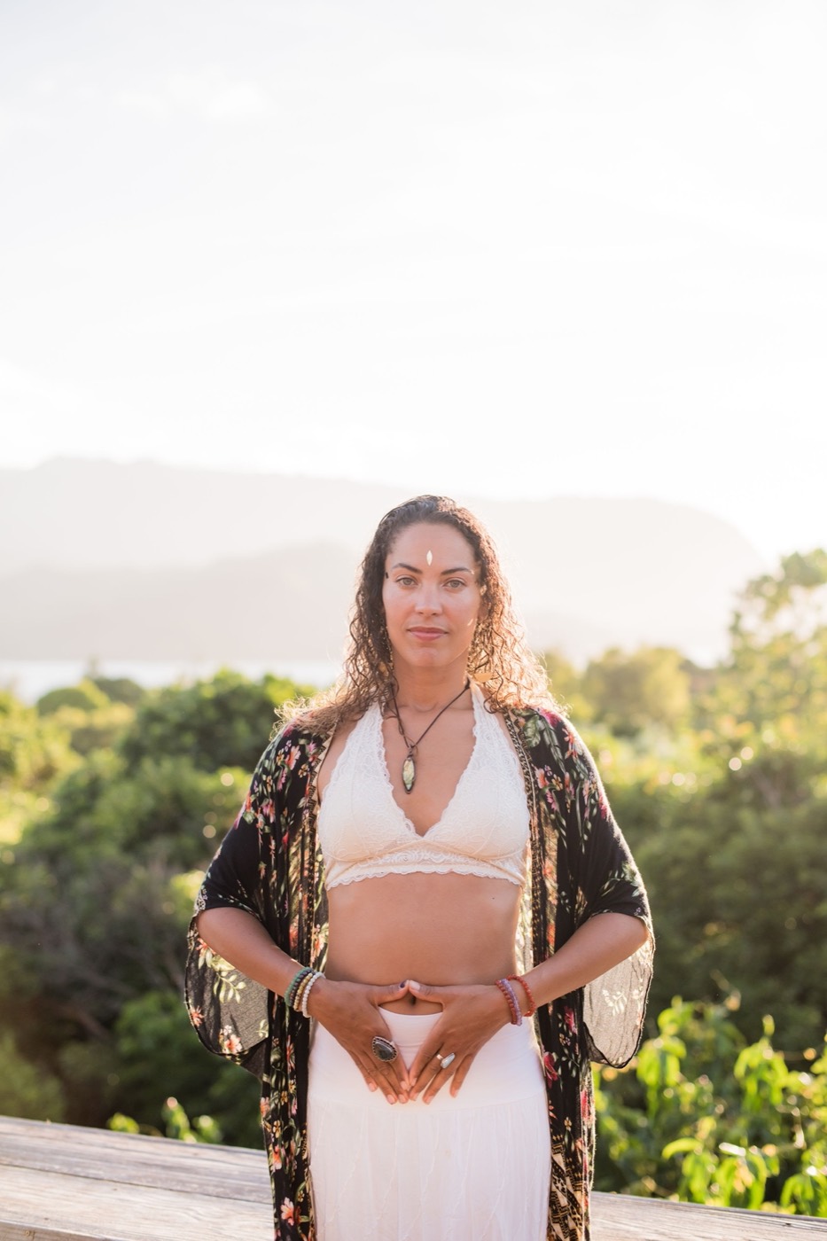 Donica with her hands resting over her lower belly, a grounding energy-healing gesture